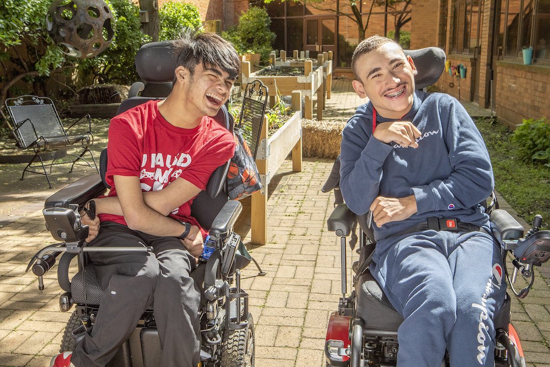 Two Henry Viscardi School students in wheelchairs smiling and laughing together