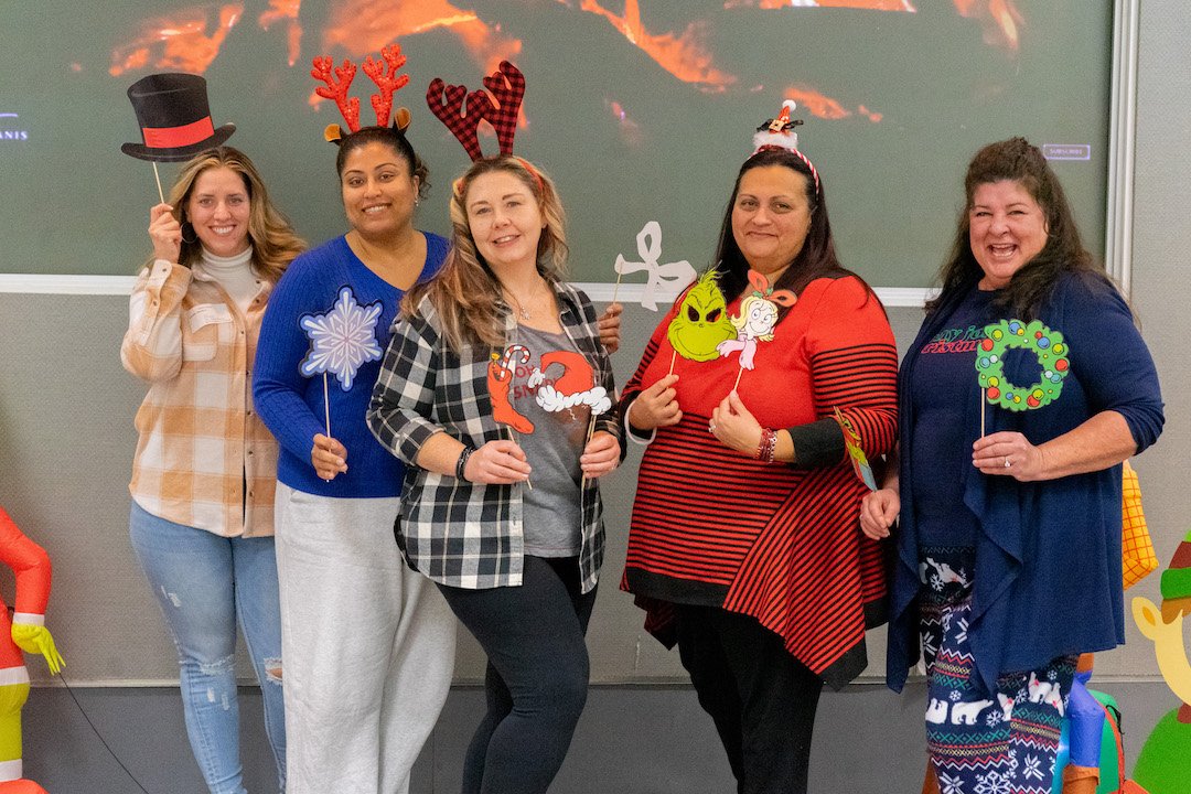 Five SEPTA women posing with various holiday accessories in hand