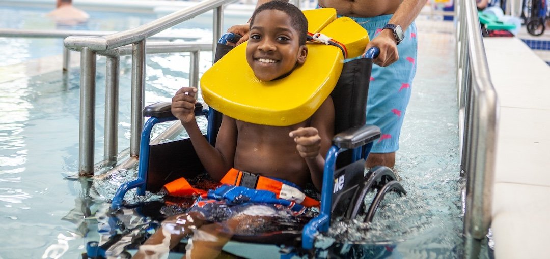 Young man in a wheelchair wheeling into an accessible pool